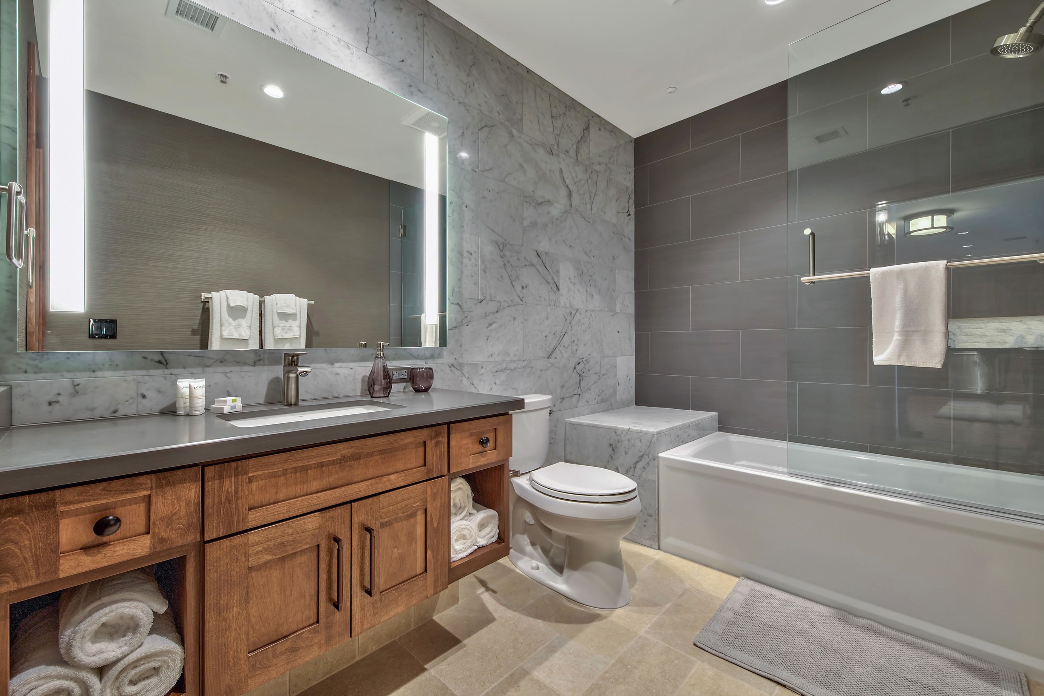 Une salle de bain moderne avec un meuble-lavabo en marbre, des toilettes et une douche à parois de verre.