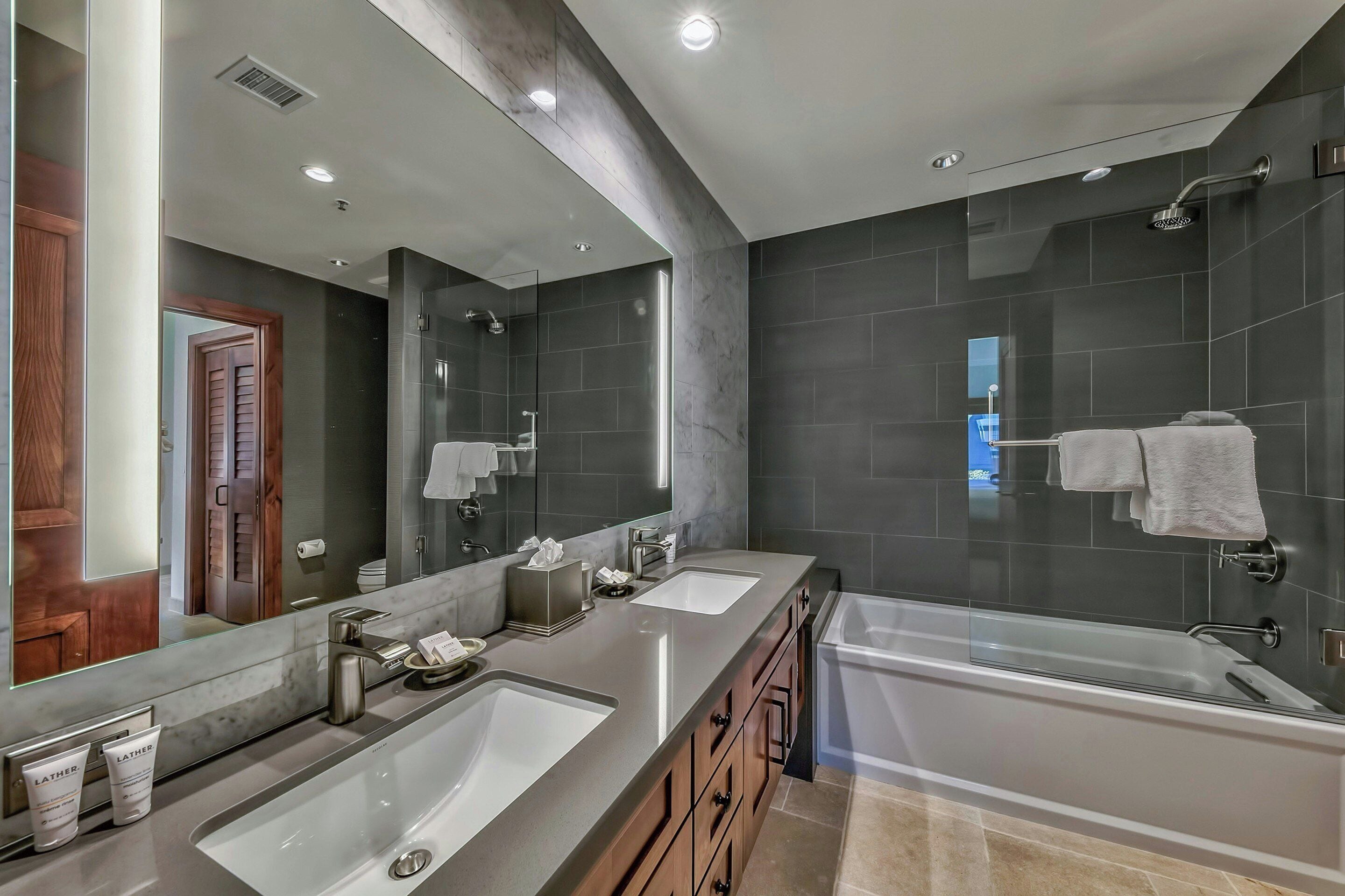 Une salle de bain moderne avec deux lavabos, une grande baignoire et une douche à l’italienne.