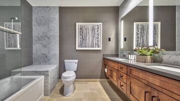 Un baño moderno con bañera, inodoro y tocador con espejo.