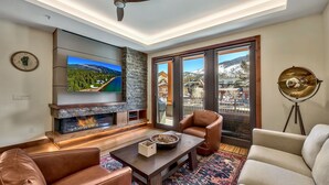 A modern living room with a fireplace, leather sofas, a coffee table, and a large TV.