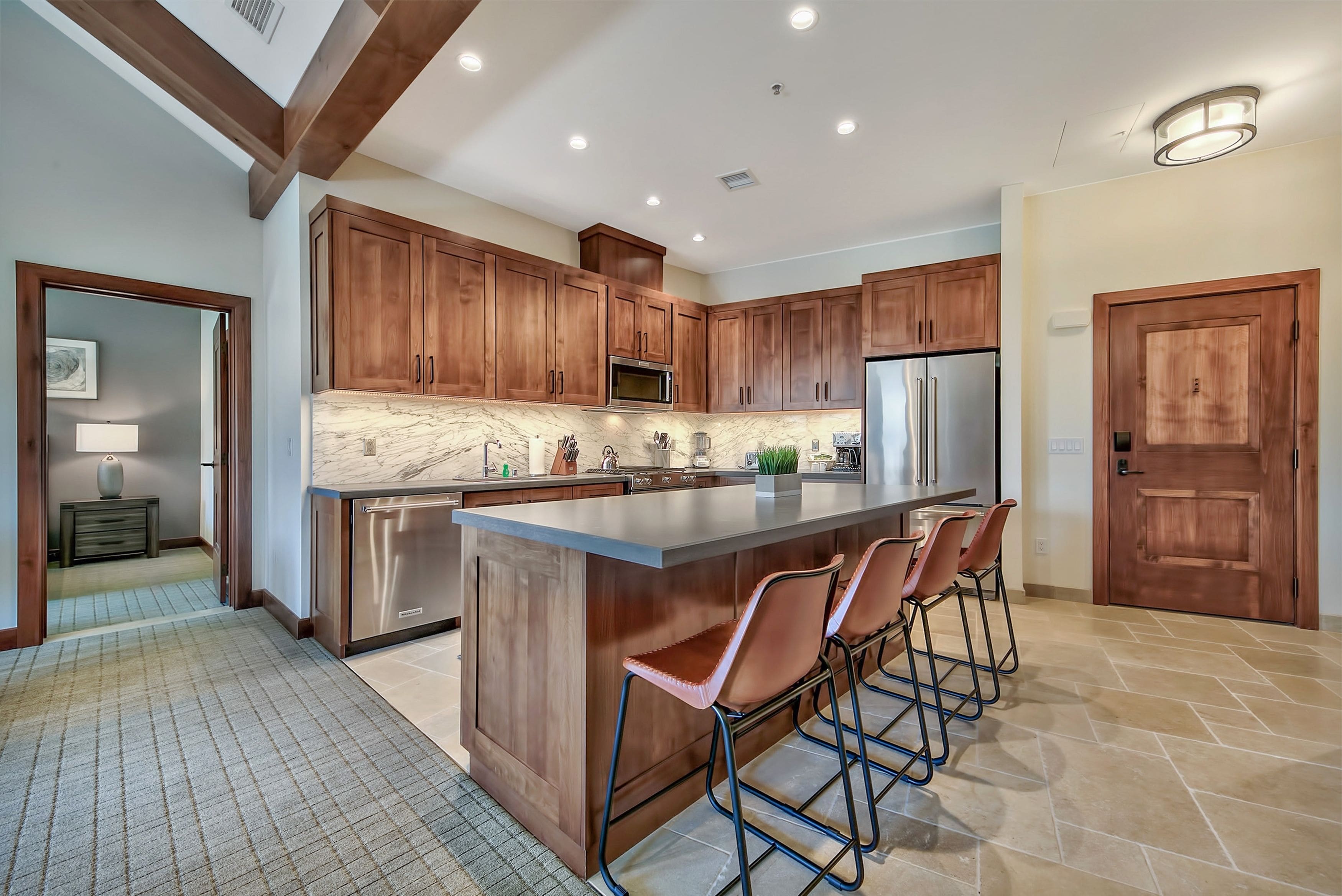 A modern kitchen with wooden cabinets, stainless steel appliances, and a marble countertop.