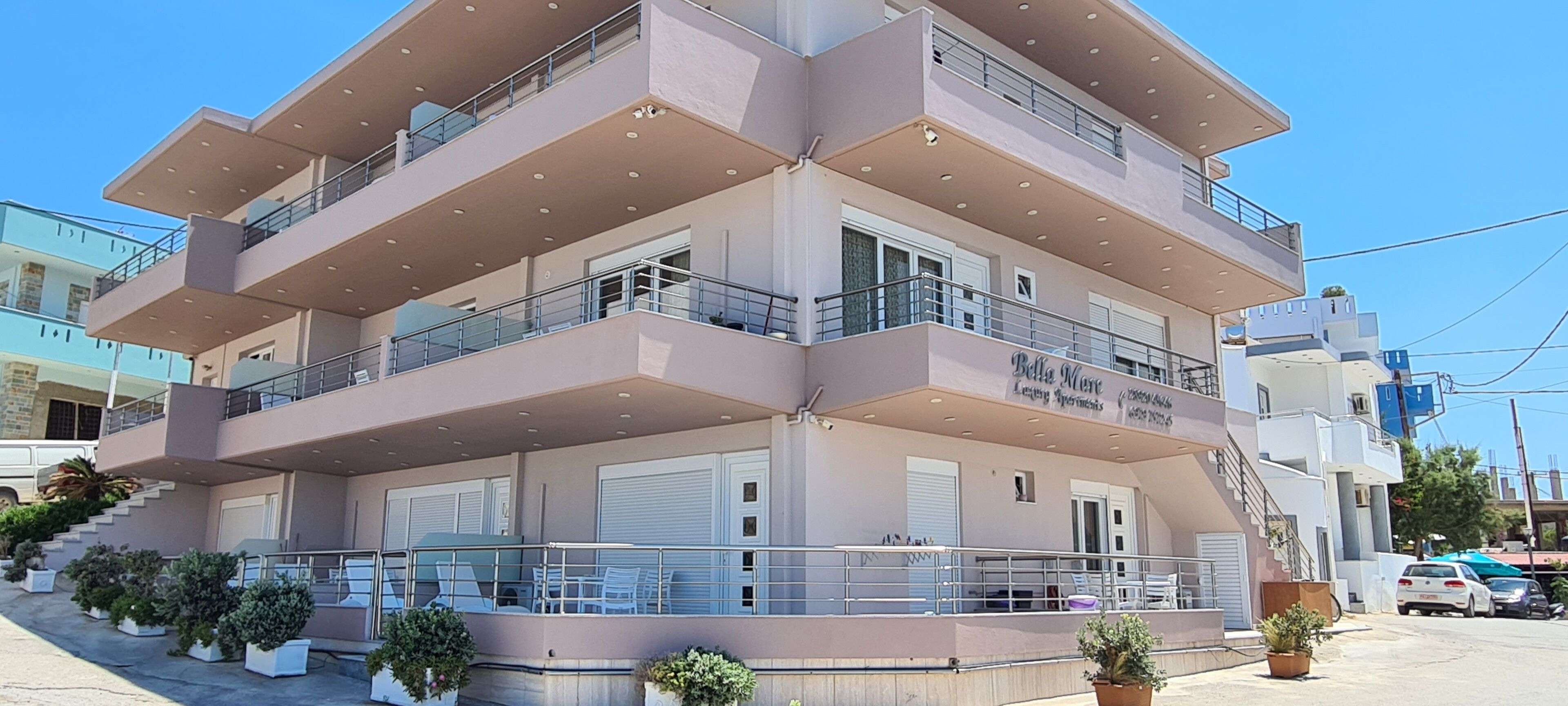 A multi-story hotel with balconies, a staircase, and potted plants.