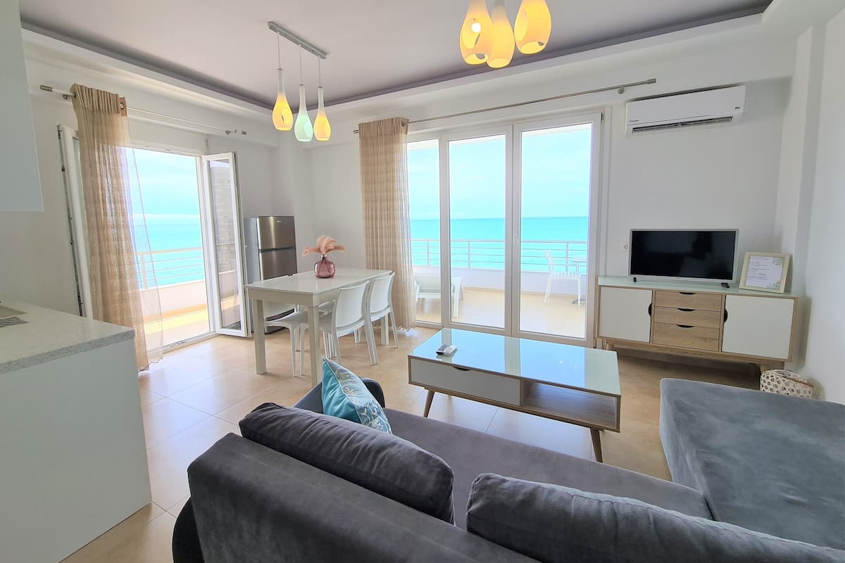 Een moderne woonkamer met een bank, een televisie en een eethoek met een tafel en stoelen.