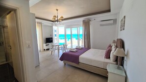 A bedroom with a bed, a desk, and a view of the ocean.