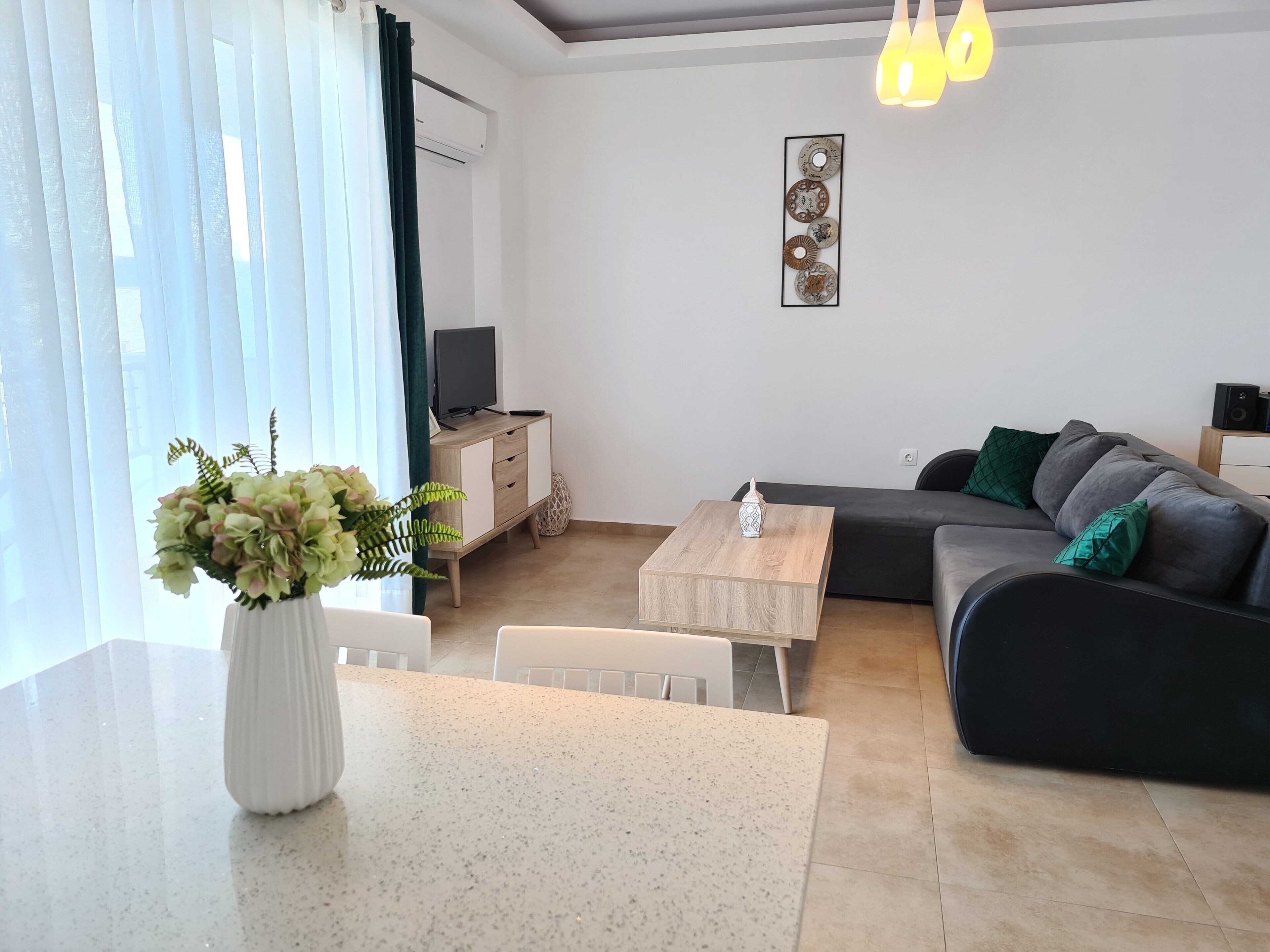 A modern living room with a sofa, a coffee table, a TV on a stand, and a decorative wall piece.