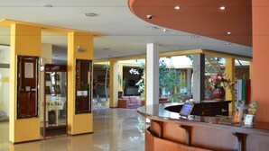 A hotel lobby with a reception desk, seating area, and a large window with a view of the outdoors. - Bankya Palace (Sofia)