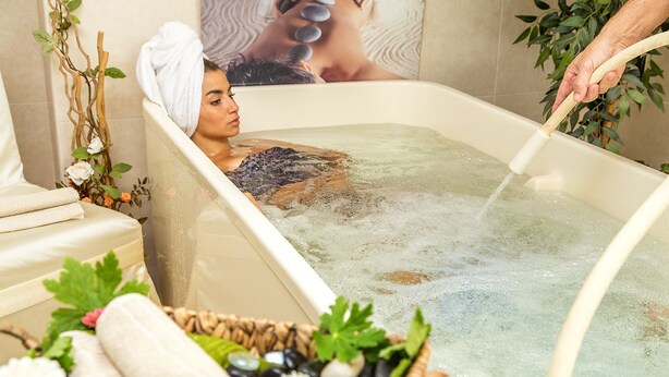 A spa bath with a person in it, surrounded by natural elements like plants and stones. - Bankya Palace (Sofia)