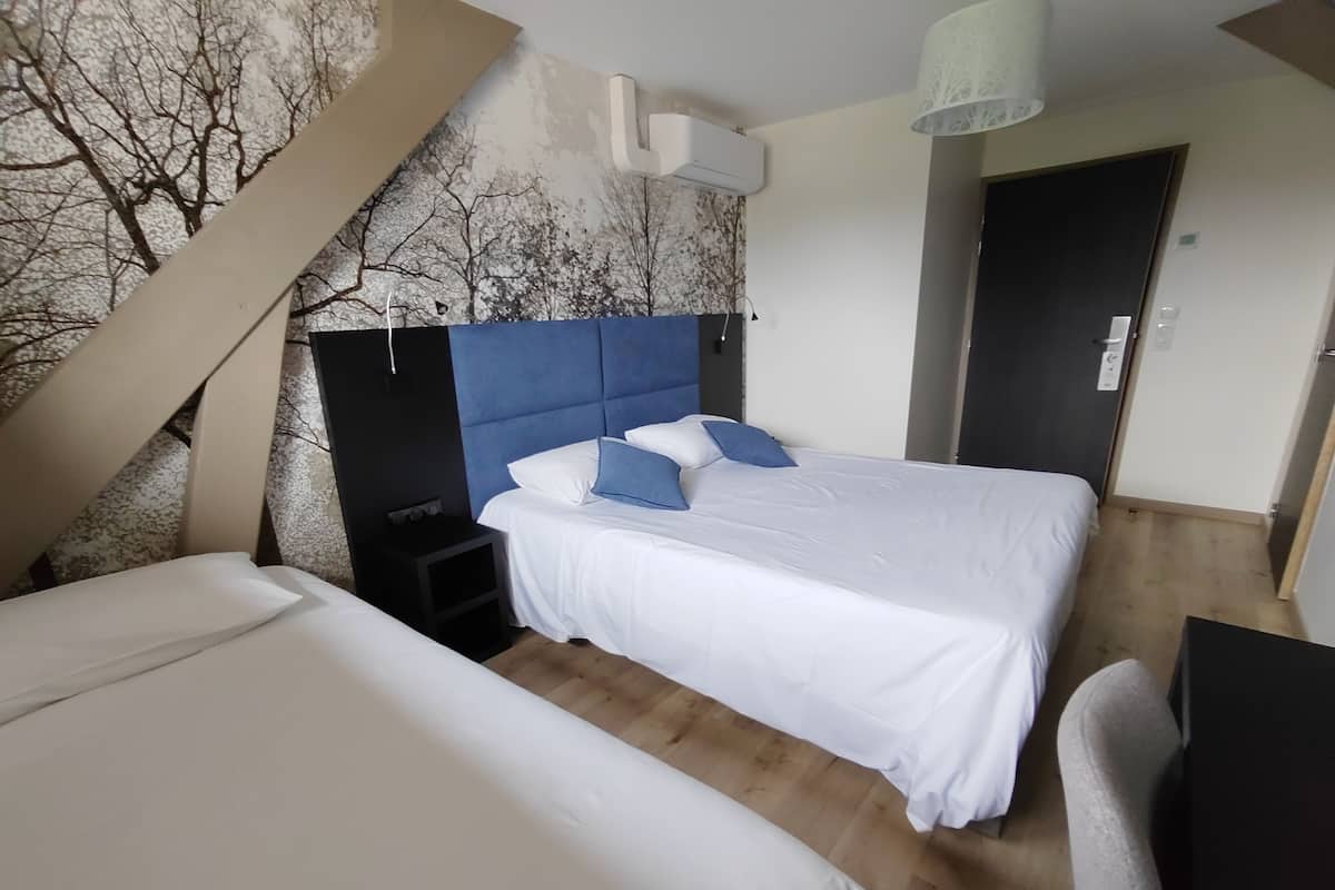 Een slaapkamer met twee bedden, een nachtkastje, een wandairconditioner en een deur.