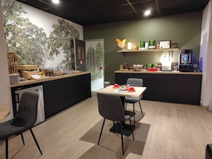 Een moderne keuken met een eethoek, een aanrecht met diverse spullen en een muur met een muurschildering.