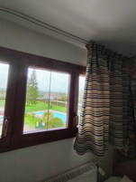 Habitación con una ventana grande que da a una piscina y follaje.