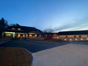 Un edificio con letrero de restaurante, zona de estar exterior cubierta y estacionamiento.