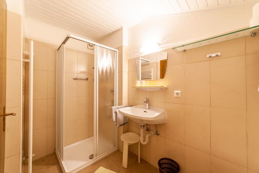 A bathroom with a shower, sink, and mirror.