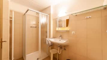 A bathroom with a shower, sink, and mirror.