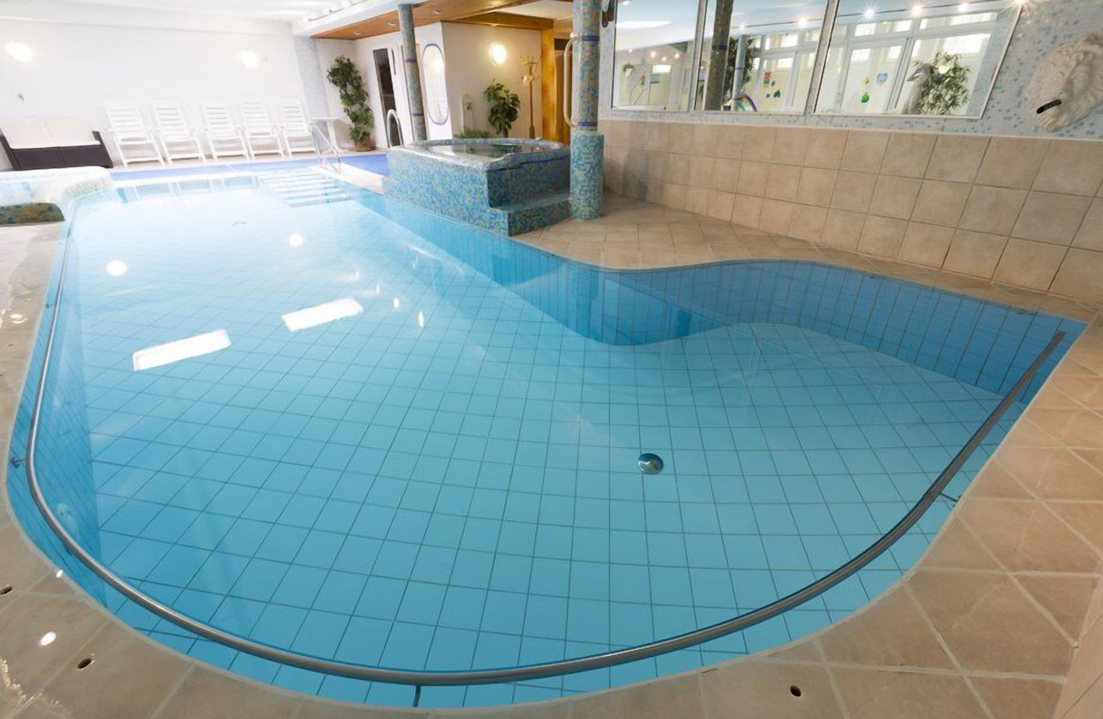 An indoor swimming pool with a tiled floor and a hot tub area.