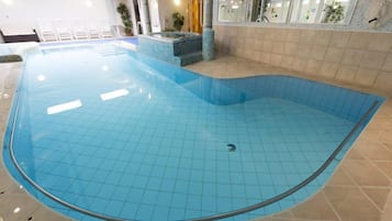 Ein Innenpool mit gefliestem Boden und einem Whirlpoolbereich.