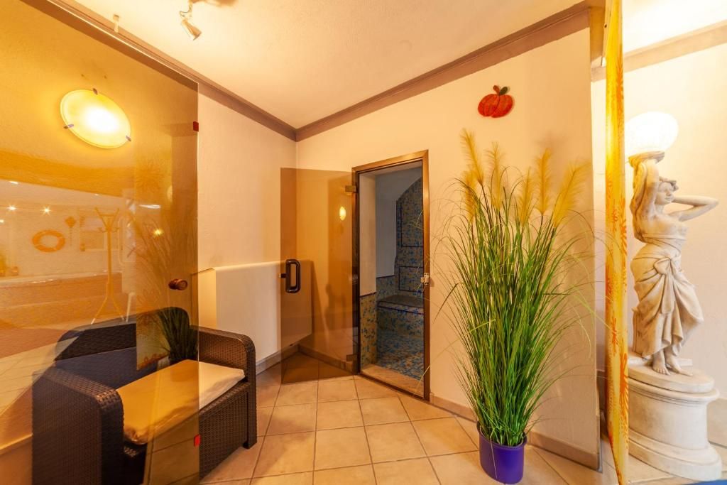 Une chambre d’hôtel avec une cloison en verre, un lit, une plante en pot et une statue.