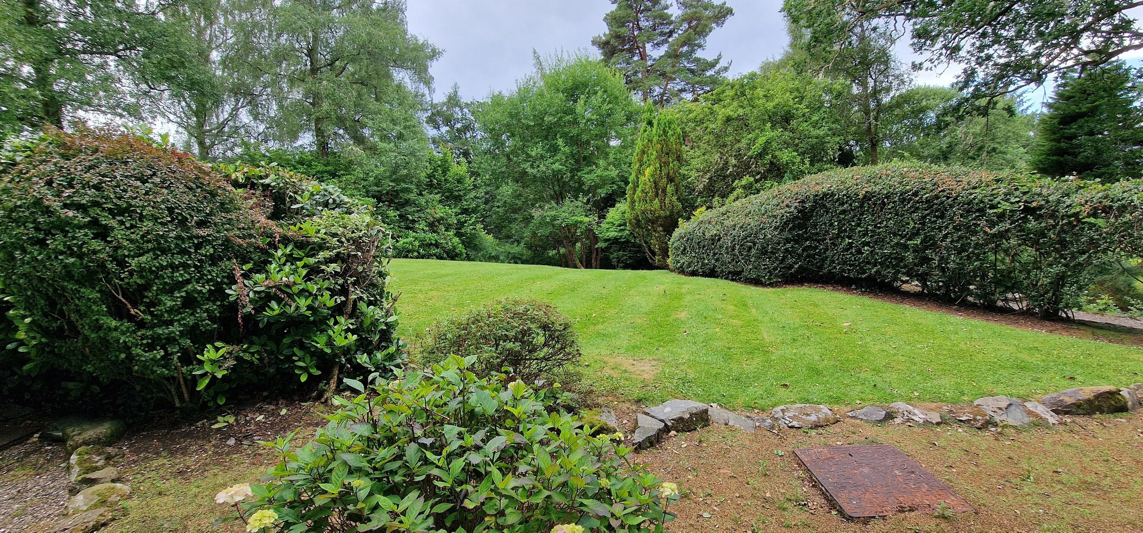 Un jardin bien entretenu, avec des haies soigneusement taillées et une pelouse verdoyante.