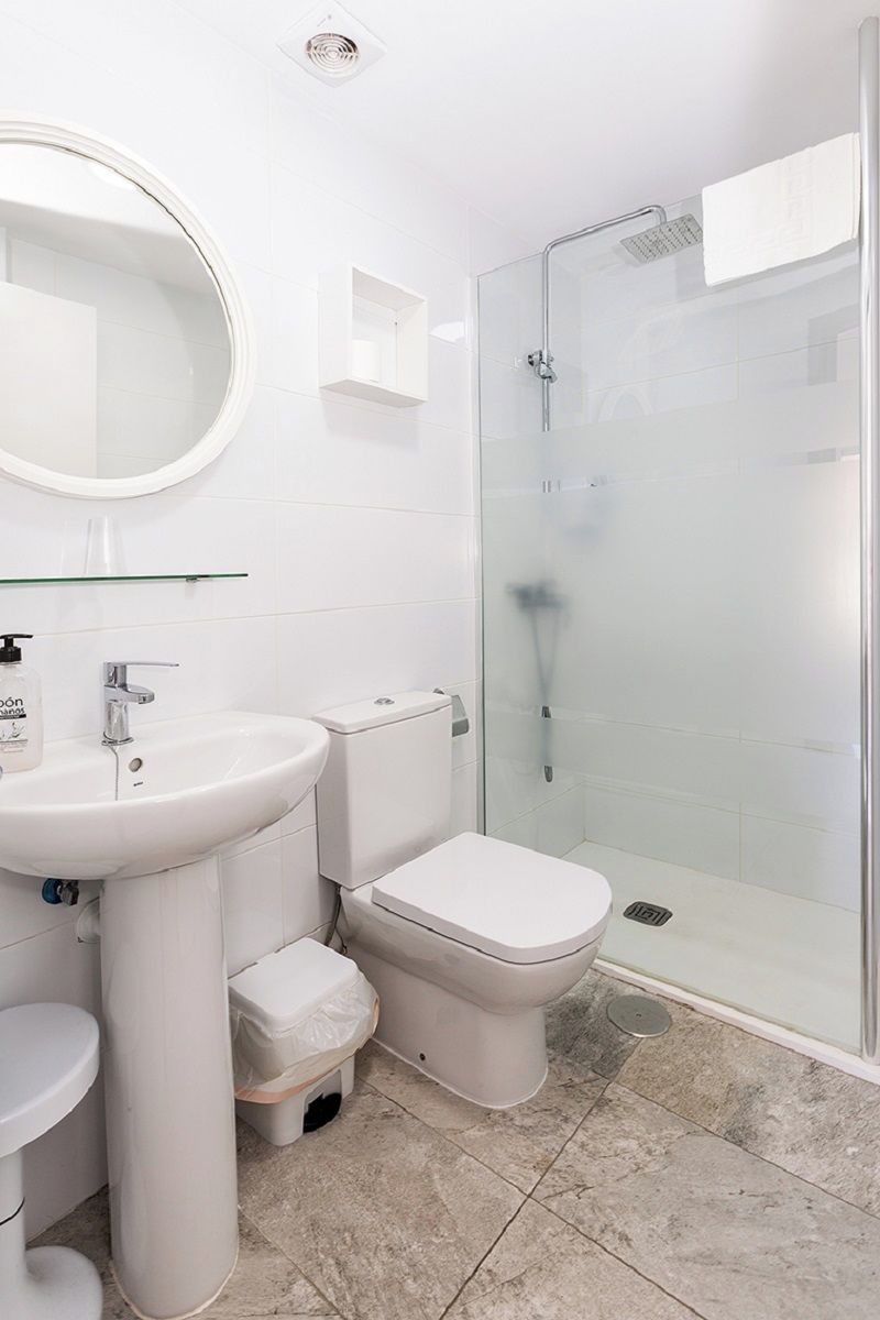 A bathroom with a white sink, toilet, and glass-enclosed shower.