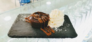 A dessert on a slate plate with a caramel drizzle and a scoop of vanilla ice cream. - Hostal El Mercat (Villajoyosa)