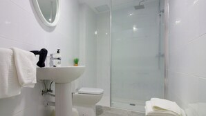 A modern bathroom with a glass-enclosed shower, a white sink, and a toilet. - Hostal El Mercat (Villajoyosa)