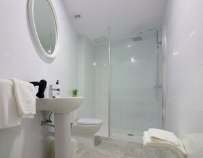 A modern bathroom with a glass-enclosed shower, a white sink, and a toilet. - Hostal El Mercat (Villajoyosa)
