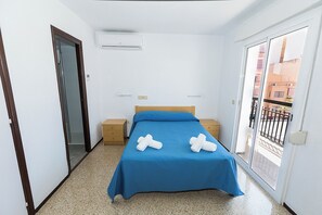 A bedroom with a bed, two bedside tables, a window, and an air conditioning unit. - Hostal El Mercat (Villajoyosa)
