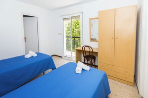 A room with two beds, a desk, a wardrobe, and a door leading outside. - Hostal El Mercat (Villajoyosa)