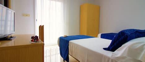 A hotel room with a bed, a desk, a television, and a window with curtains.