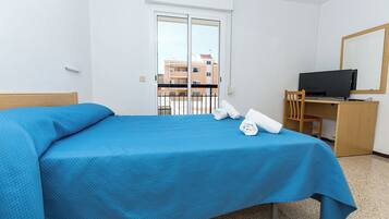 Habitació d'hotel amb llit, escriptori i ordinador, i televisió.