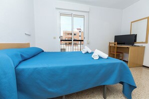 Una habitación de hotel con una cama, un escritorio con computadora y televisión.