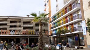 A commercial building with a sign reading "mercat" and a colorful multi-story structure with balconies. - Hostal El Mercat (Villajoyosa)