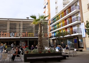 A commercial building with a sign reading "mercat" and a colorful multi-story structure with balconies. - Hostal El Mercat (Villajoyosa)