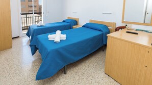 A hotel room with two beds, a wooden desk, and a mirror. - Hostal El Mercat (Villajoyosa)