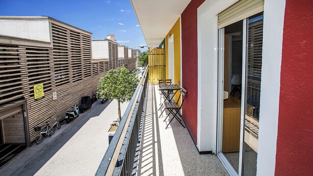 A balcony with a view of parked bicycles and scooters, a small tree, and a table with chairs. - Hostal El Mercat (Villajoyosa)