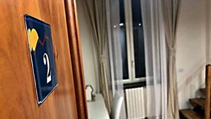 A hotel room with a wooden door, a window with curtains, a radiator, and a staircase. - DayBreak B&B (Naples)