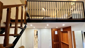 A multi-level interior with a wooden staircase, a sofa, a door leading to a bathroom, and a kitchen area. - DayBreak B&B (Naples)