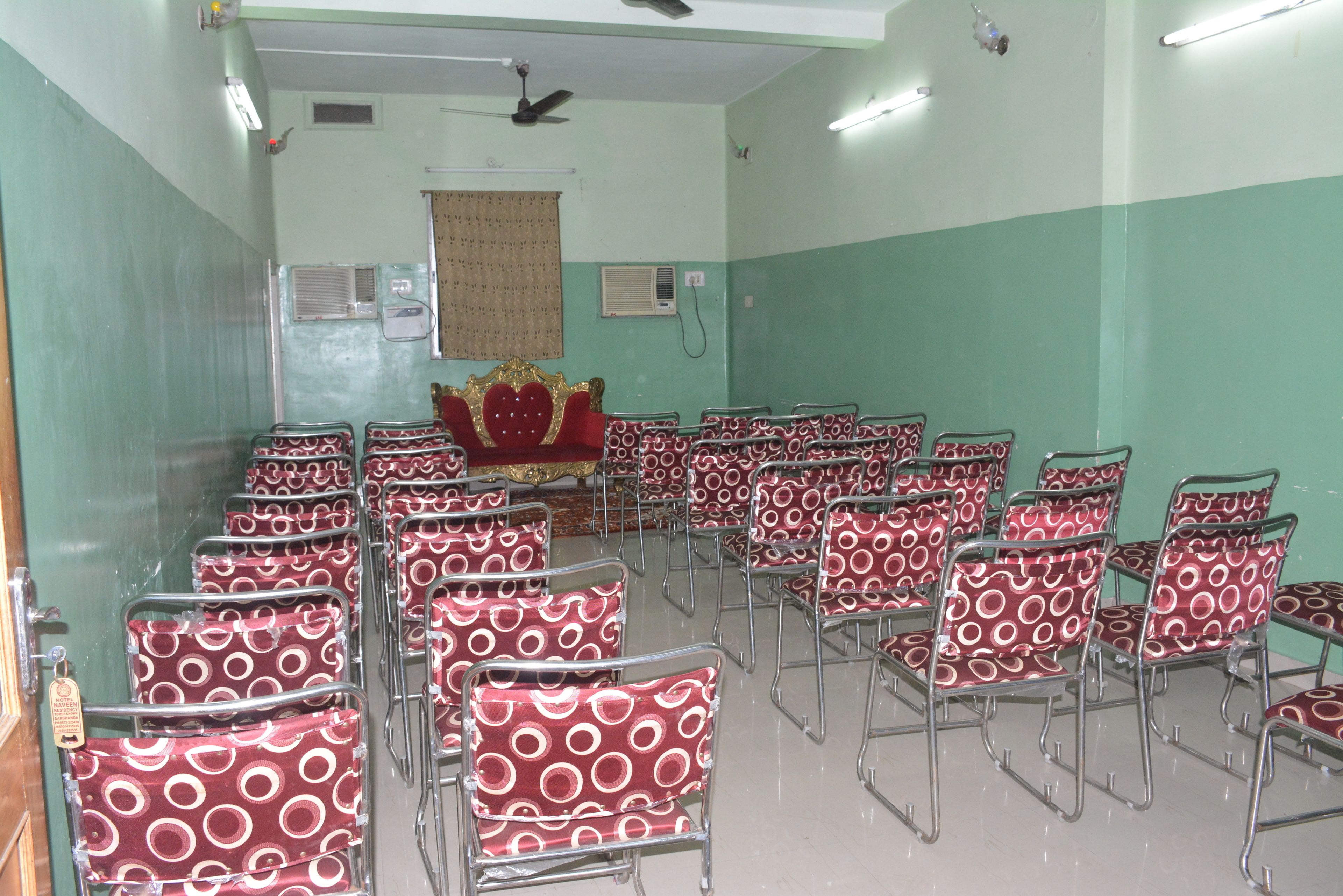 A conference room with rows of chairs, a podium, and a ceiling fan.