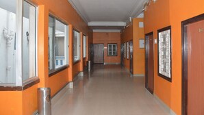 A corridor with orange walls, doors, and a trash bin. - Hotel Naveen Residency (Darbhanga)
