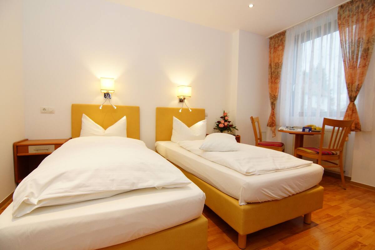 A hotel room with two beds, a desk, and a chair.