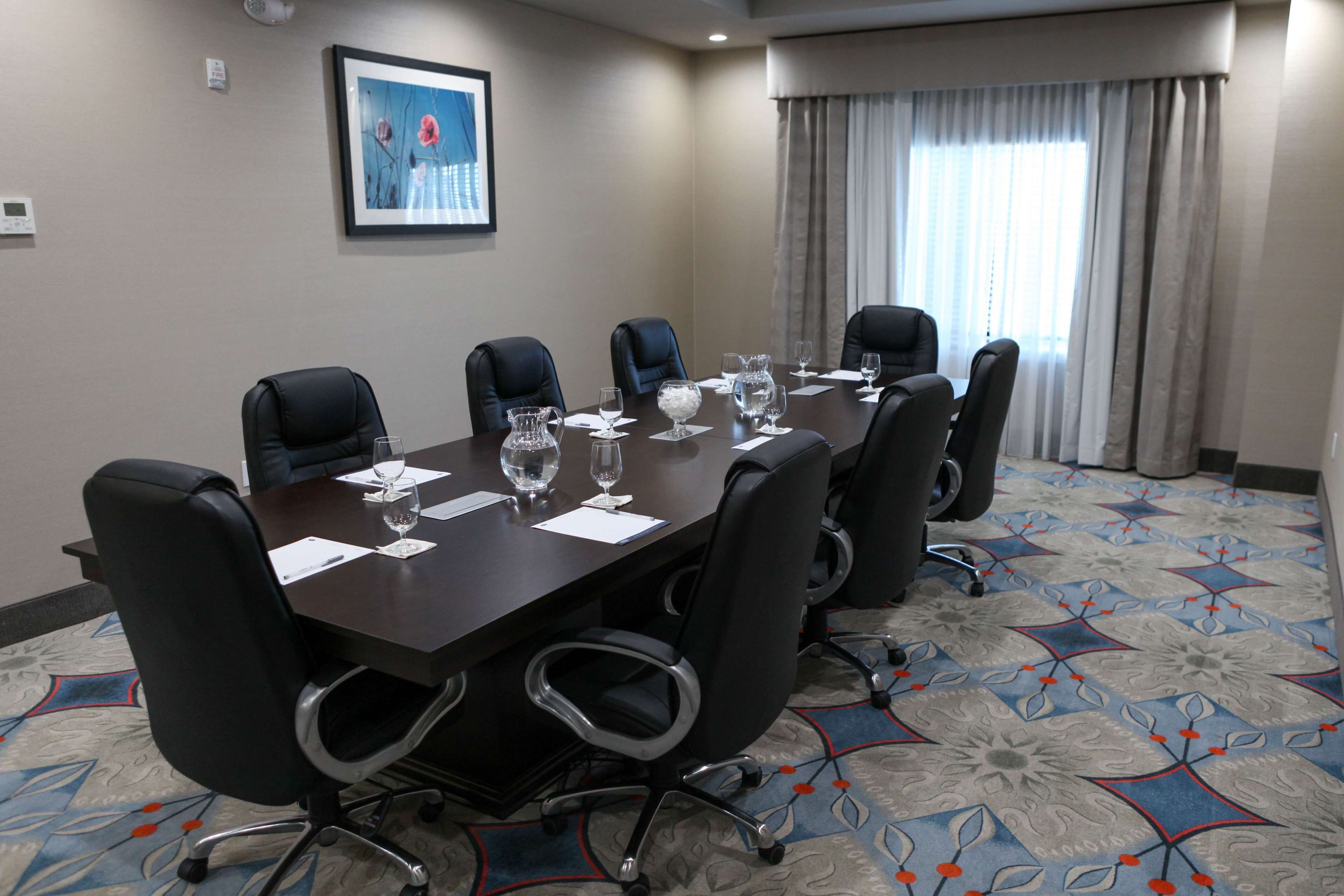 Un salón de conferencias con una mesa grande, seis sillas y un cuadro en la pared.