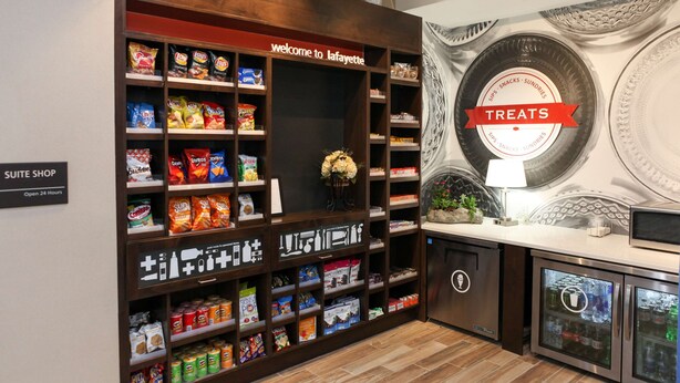 A suite shop with shelves of snacks and drinks, a welcome sign, and a decorative wall with a 'Treats' sign. - Hampton Inn & Suites Lafayette Medical Center, CO (Lafayette)