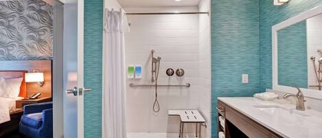 A modern bathroom with a shower, vanity, and a small table.