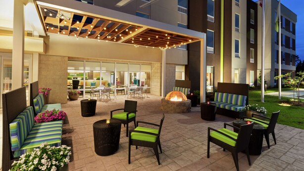 Un patio al aire libre con mobiliario, una chimenea y una sección cubierta con guirnaldas de luces.