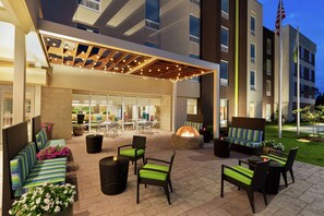 An outdoor patio area with seating, a fire pit, and a covered section with string lights. - Home2 Suites by Hilton Savannah Airport (Pooler)