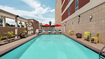 Una piscina al aire libre, sombrillas, sillones reclinables de piscina