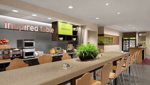Un restaurante moderno con una barra larga, asientos y una zona de cocina.