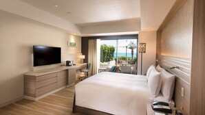 Habitación de hotel con una cama grande, un televisor de pantalla plana, un escritorio con una silla y vistas al exterior.