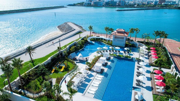 Un resort con una amplia piscina, tumbonas y una zona de playa.