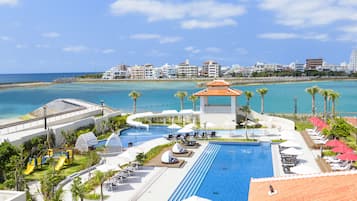 A resort with a large swimming pool, lounge chairs, and a view of the beach and ocean.