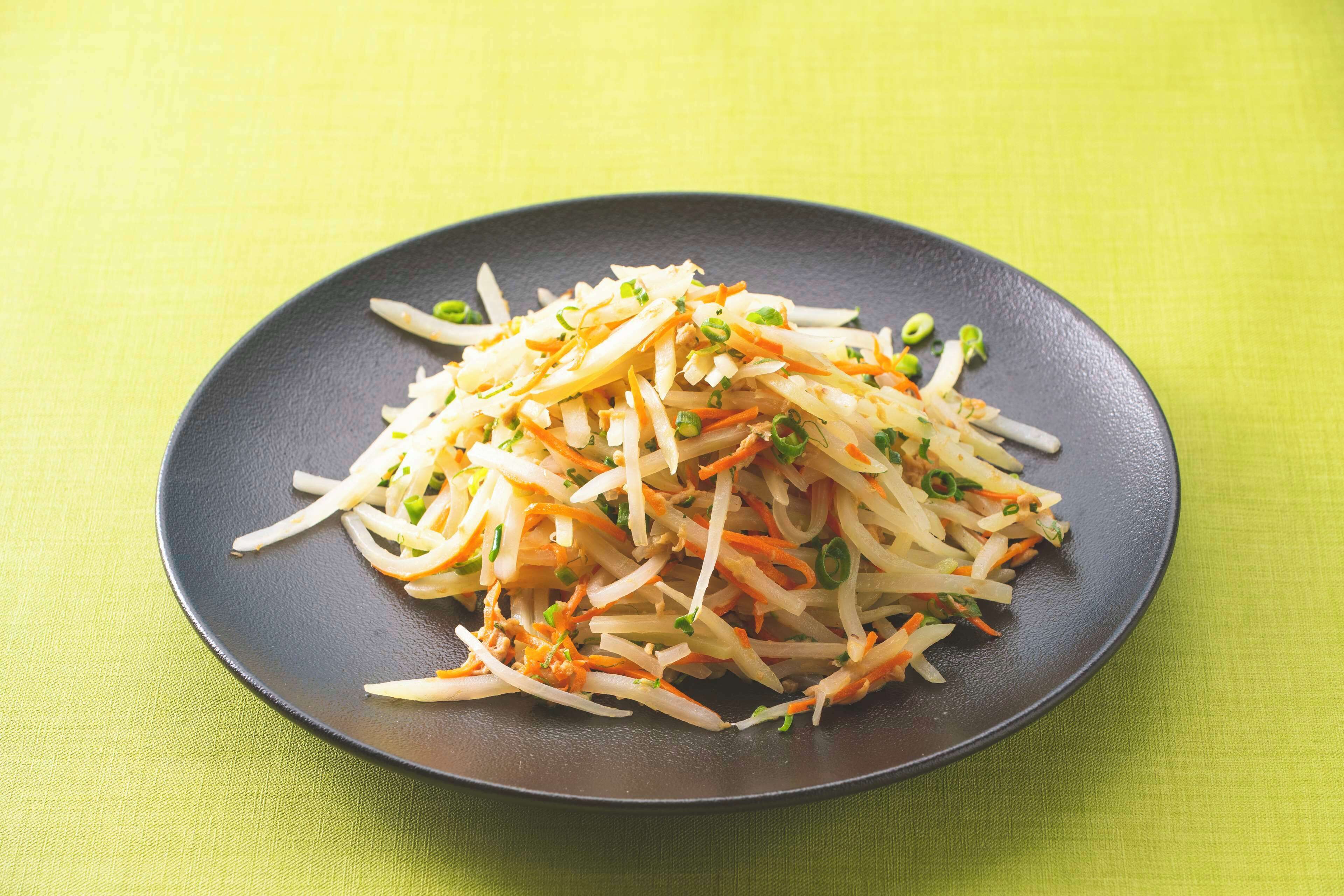 A plate of shredded vegetables on a dark plate.